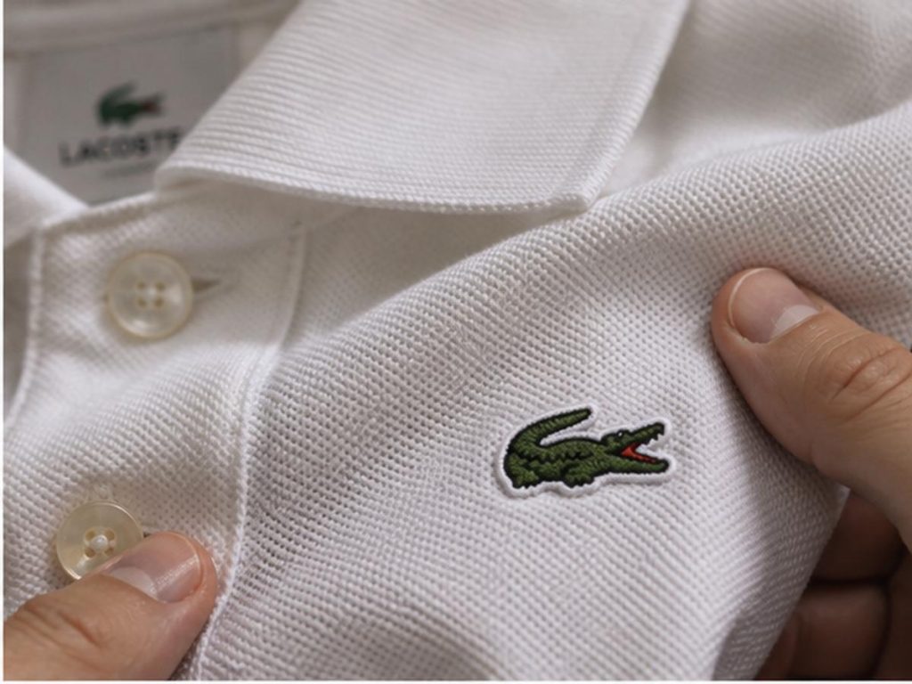 Крупный план ткани petit piqué и вышитого крокодила Lacoste
